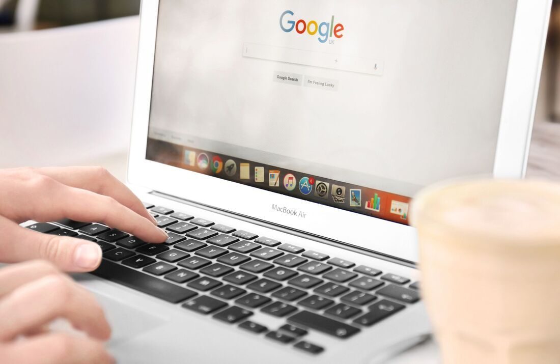 A laptop open to the Google search page, with hands on the keyboard