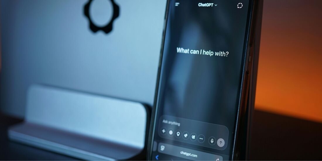 A phone showing an AI chat assistant asking, What can I help with?