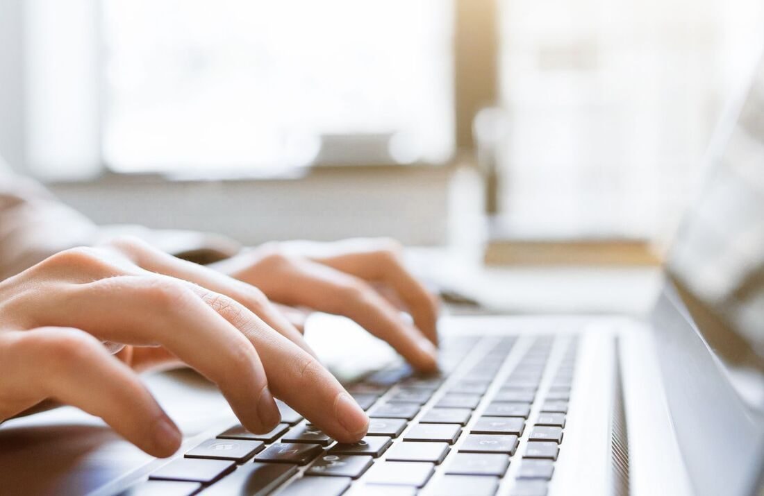 Close-up of hands typing on a laptop keyboard in soft natural light