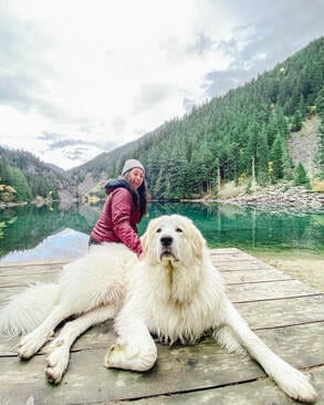 Jessica's wife and their Great Pyrenees on a dock by a mountain lake